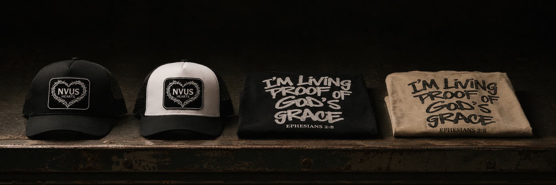 NVUS Hearts trucker hats and folded Living Proof tees lined up on a workbench